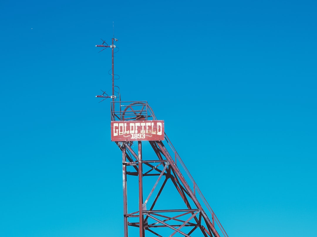 Rusty metal structure with goldfield sign against blue sky