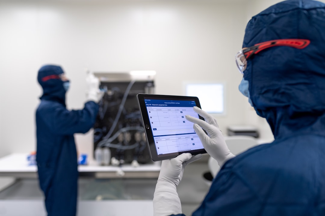 a few people in blue lab coats looking at a computer screen