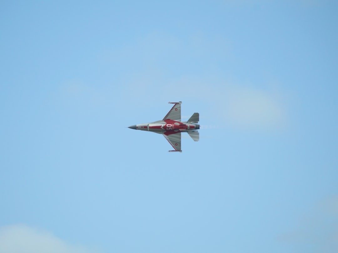 A red and white jet flying through a blue sky