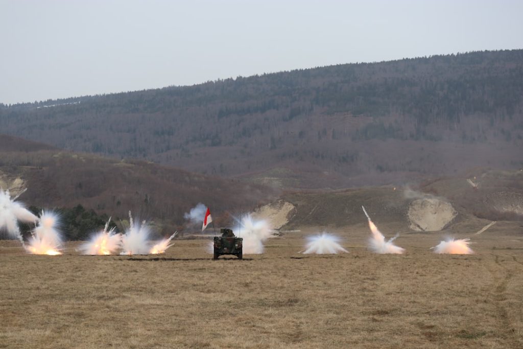 Armored vehicle fires multiple rounds in a field.